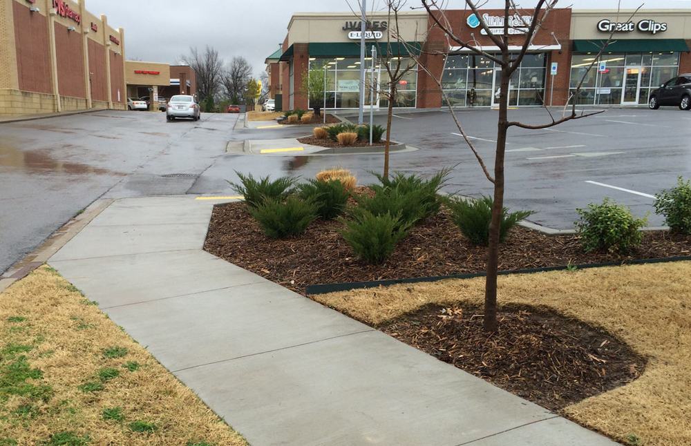 A sidewalk with many curb cuts.  (Source)