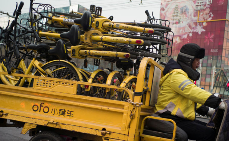 A worker transports bicycles for bike-sharing startup Ofo in Beijing, China.