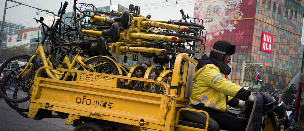 A worker transports bicycles for bike-sharing startup Ofo in Beijing, China.