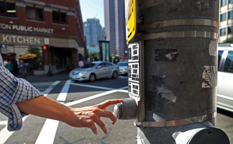 BOSTON, MA - JULY 21: A pedestrian presses a traffic signal button at Congress and Sudbury Streets in Boston on Jul. 21, 2017. The vast majority of these buttons that dot downtown neighborhoods don