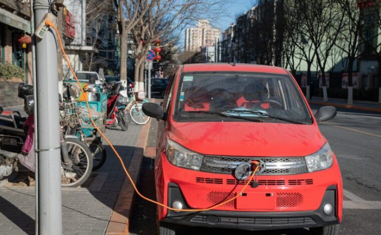 A tiny car is plugged in to charge by the side of a street  in Beijing, China on January 4, 2021.